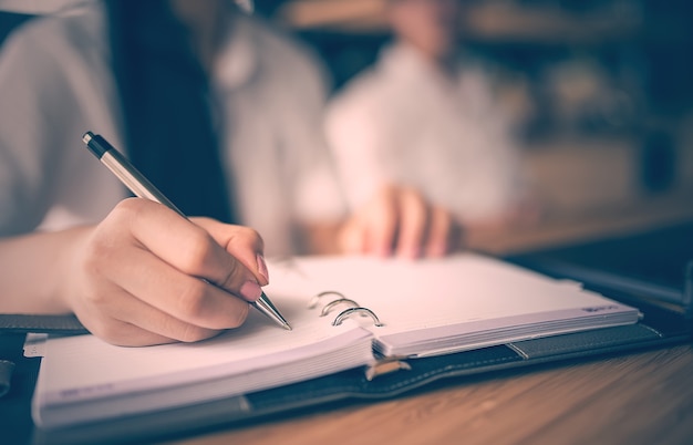 penna e scrittura della tenuta della mano della donna sul taccuino