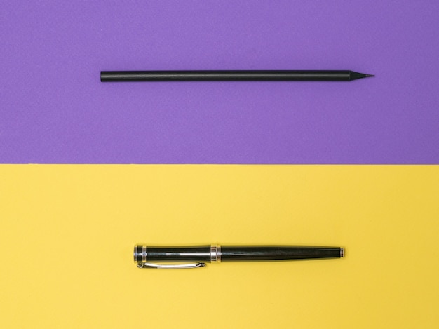 Penna nera e matita nera su sfondo giallo e viola. Cancelleria alla moda.