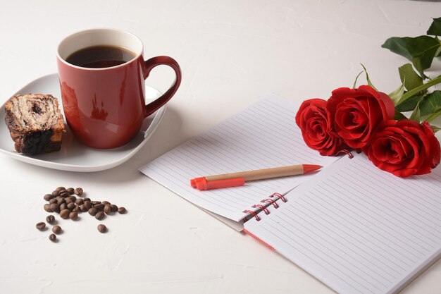 Penna per taccuino con tazza di caffè e fiori di rosa Pausa caffè mattutina