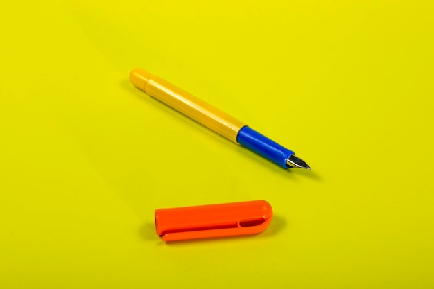 Penna stilografica gialla con cappuccio arancione su sfondo giallo