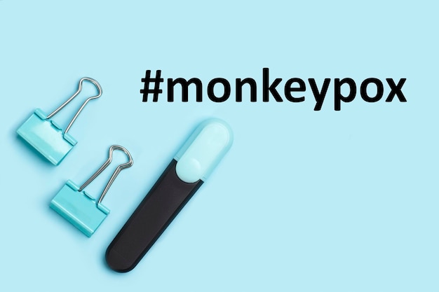 Pennarello e raccoglitori su sfondo blu con hashtag monkeypox virus
