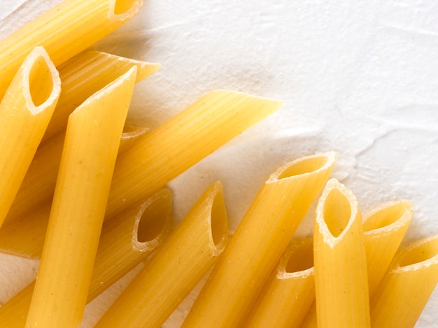 Penne crudo della pasta su fondo bianco