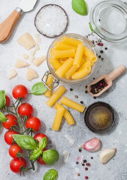 Penne in vasetto di vetro con parmigiano e pomodori basilico con aglio e olio su sfondo chiaro Vista dall'alto