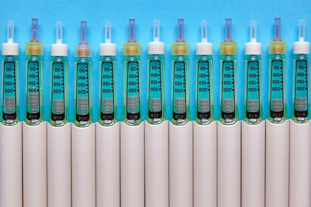Penne per siringa con insulina allineate in fila su sfondo blu Vista dall'alto con spazio per la copia Disposizione piatta