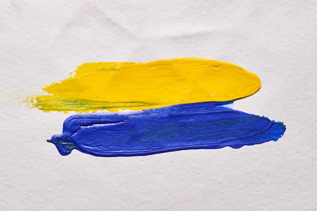 Pennellate gialle e blu di vernice su sfondo astratto di carta bianca