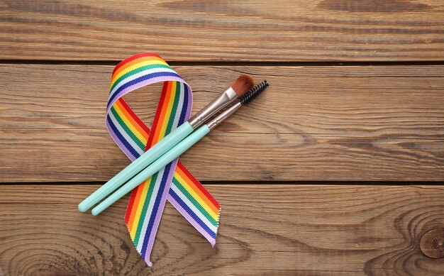 Pennelli per il trucco con simbolo del nastro dell'orgoglio del nastro arcobaleno LGBT su sfondo di legno Vista dall'alto