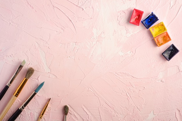 Pennelli, strumenti dell'artista per attingere la superficie strutturata di rosa, vista superiore, spazio della copia