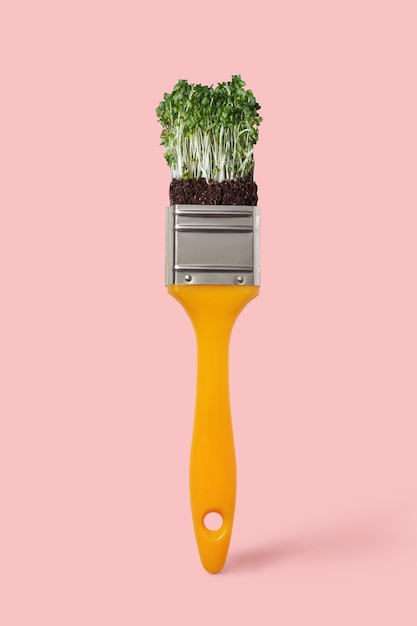 Pennello creativo con microgreen biologico fresco vegetale su uno sfondo colorato dell'anno 2019 Living Coral, posto per il testo. Pittura concettuale atossica.
