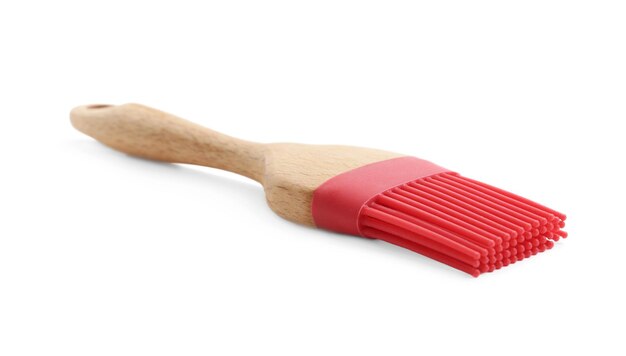 Pennello in silicone rosso con manico in legno isolato su bianco Utensile da cucina