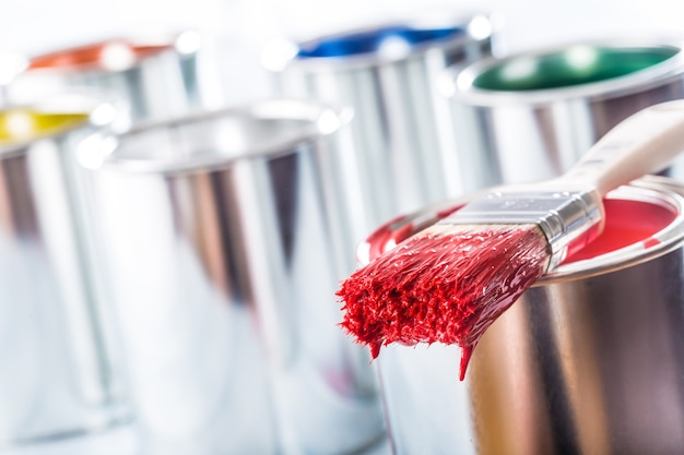 Pennello per primo piano con colore rosso sdraiato su un barattolo di vernice.