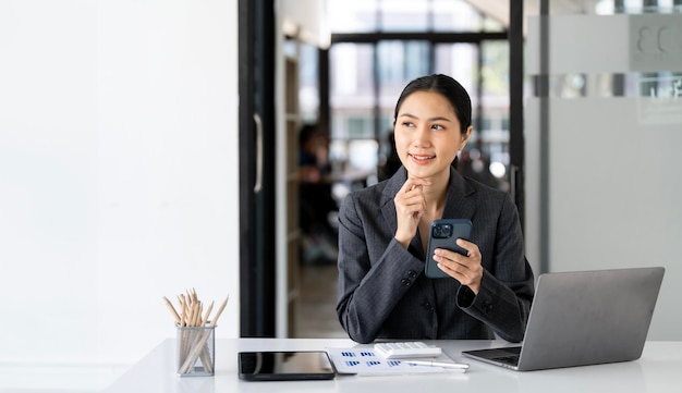 Pensando a come portare l'azienda ad altezze tecnologiche Giovane donna d'affari che usa il telefono cellulare mentre lavora nel suo ufficio