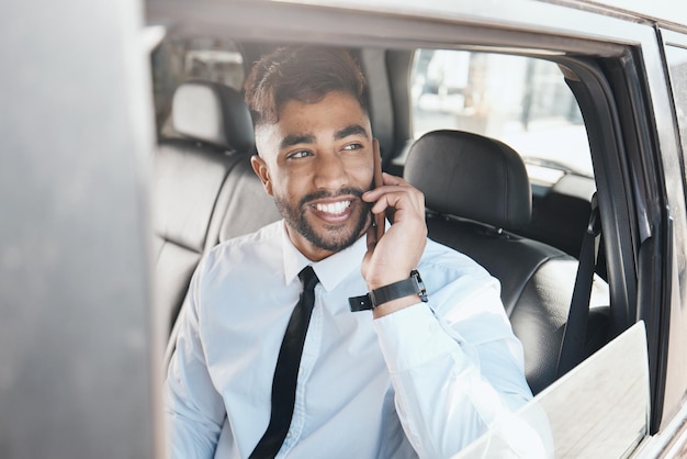 Pensare felice e uomo d'affari durante una telefonata in macchina per la comunicazione di viaggio e il lavoro Idee di sorriso e un giovane impiegato aziendale in taxi o trasporto mentre parla al cellulare al mattino