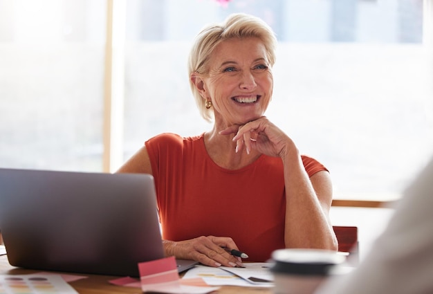 Pensiero e gestione del laptop con una donna anziana in affari seduta a un tavolo nella sala riunioni Pensiero e sorriso del computer con una donna felice al comando che lavora da sola nel suo ufficio