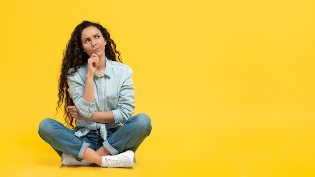 Pensiero Femminile Pensieroso Che Guarda Da Parte Seduto Su Sfondo Giallo