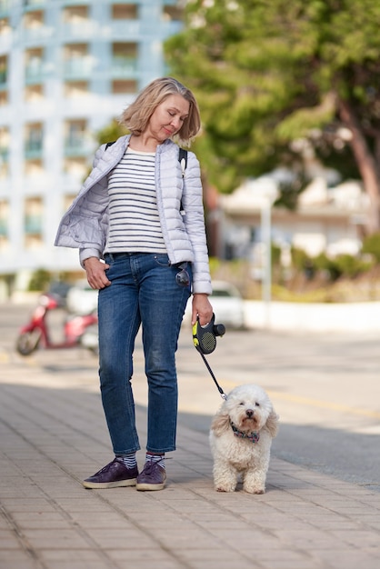 Pensionato anziano donna a piedi parco bianco cane di piccola taglia.