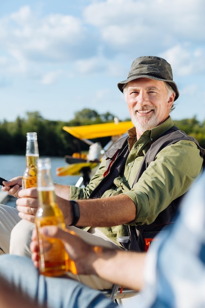 Pensionato raggiante che trascorre del tempo con un amico maschio e pesca