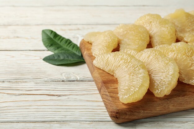 Pensione con fette di pomelo e foglie su fondo in legno