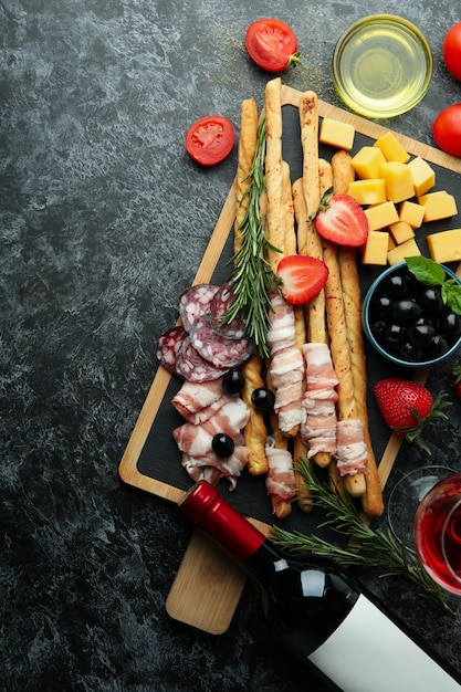 Pensione con grissini e snack e vino sul tavolo fumoso nero