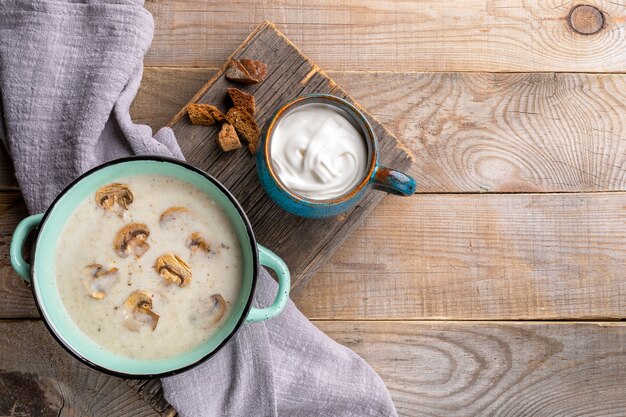 Pentola ceramica con la zuppa di funghi sulla tavola di legno