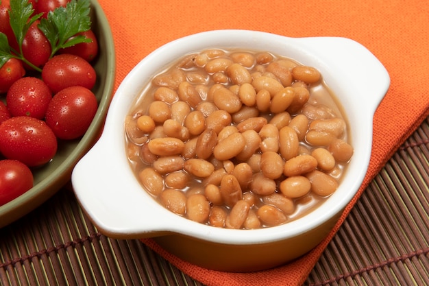 Pentola in ceramica con fagioli carioca cotti a tavola con stuoia e panno