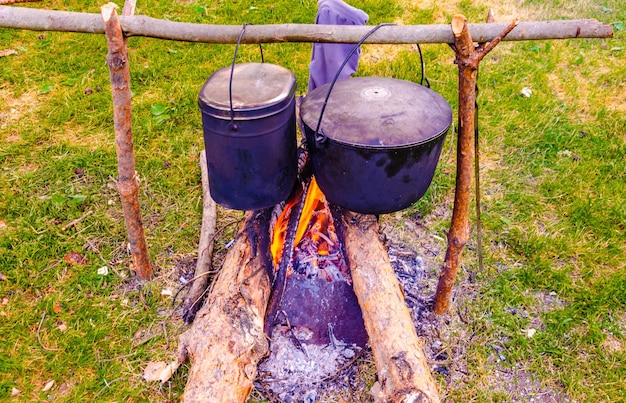 Pentole da cucina su un falò nella foresta.