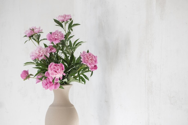 Peonia rosa in vaso di ceramica sul vecchio muro di fondo