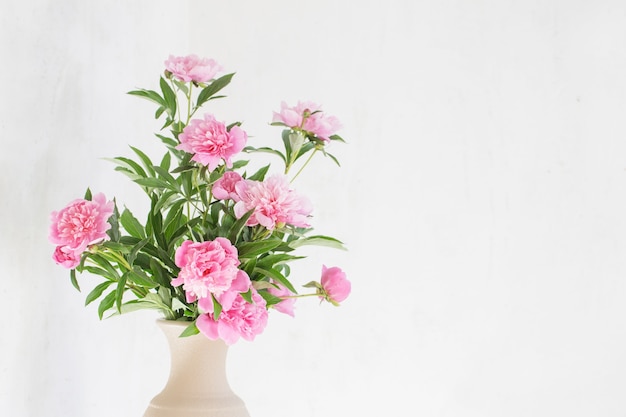 Peonia rosa in vaso di ceramica sul vecchio muro di fondo