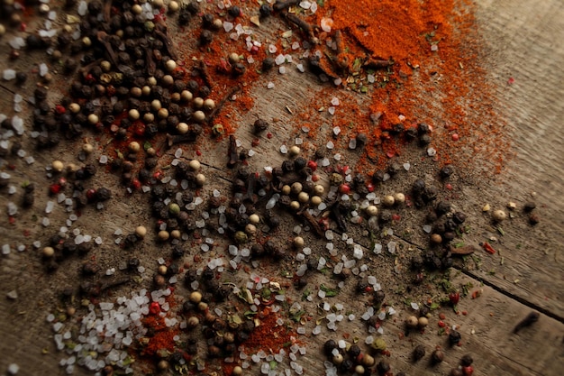 Pepe bianco e nero piselli sale marino pepe rosso polvere di chiodi di garofano spezie su uno sfondo di legno