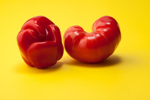 Pepe brutto e pomodoro a forma di cuore su sfondo giallo.