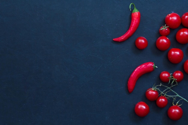 Peperoncini freschi e pomodori ciliegia su sfondo nero