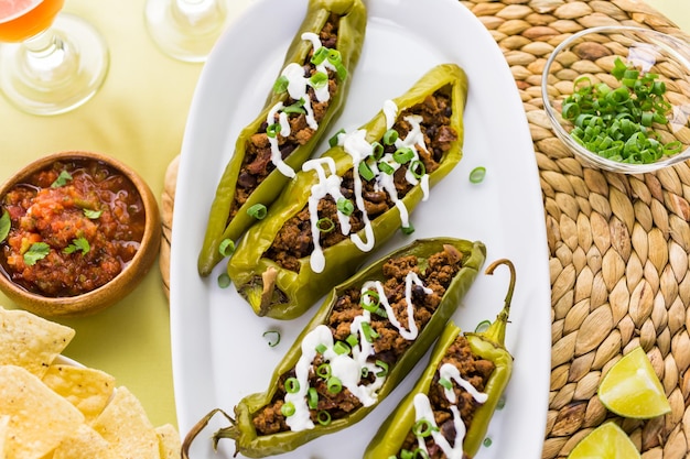 Peperoncini ripieni di manzo chipotle e fagioli guarniti con panna acida e scalogno.