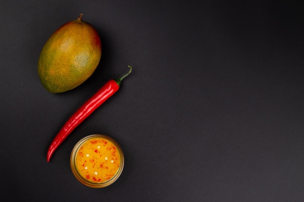 Peperoncino di mango e marmellata di peperoncino di mango su sfondo grigio scuro con spazio per il testo