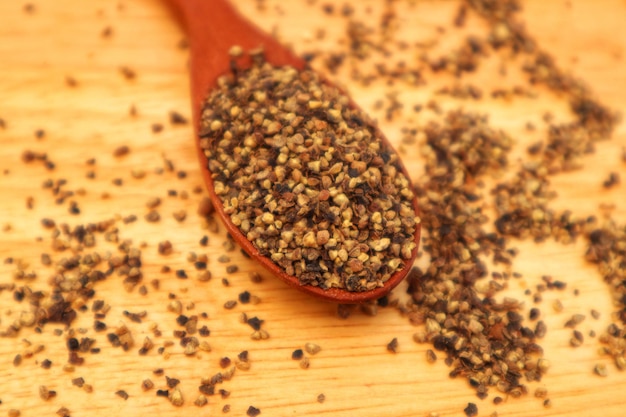Peperoncino nero schiacciato Piper nigrum L in un cucchiaio di legno e alcuni sparsi visti dall'alto