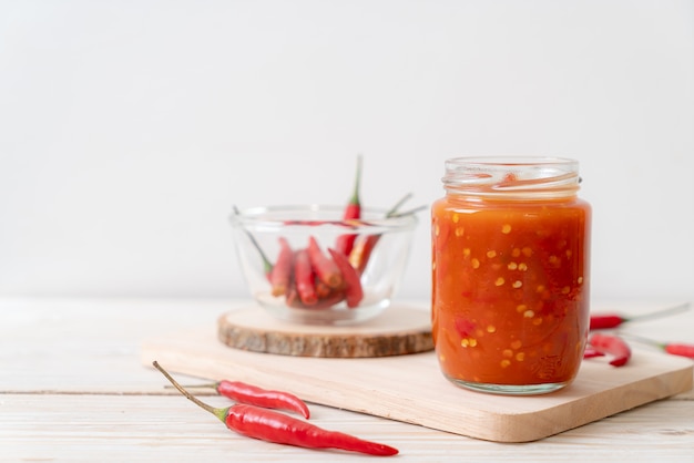 peperoncino o salsa di peperoncino in bottiglia e vaso sul tavolo di legno