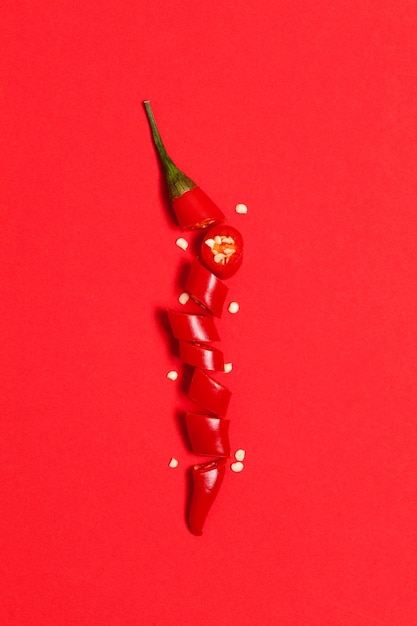 Peperoncino rosso affettato disposto su fondo rosso brillante