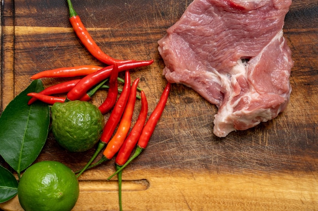 Peperoncino rosso lime e carne di maiale sul fondo del tagliere di legno