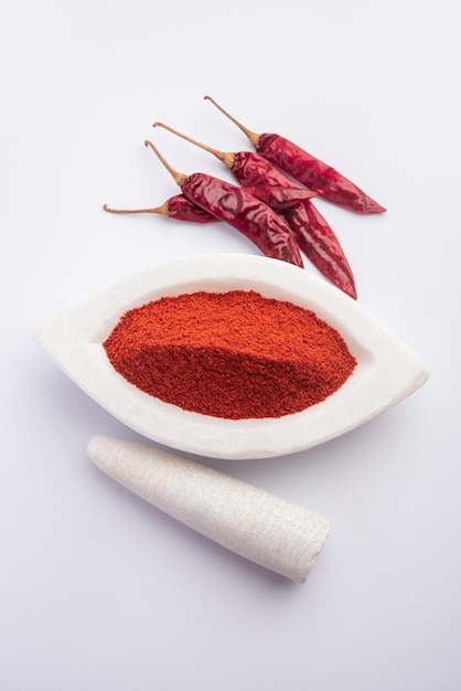 Peperoncino rosso o Lal Mirchi o mirch con polvere in una ciotola o mortaio su sfondo lunatico, messa a fuoco selettiva