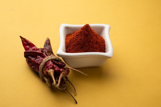 Peperoncino rosso o Lal Mirchi o mirch con polvere in una ciotola o mortaio su sfondo lunatico, messa a fuoco selettiva