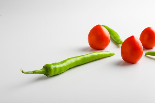 Peperoncino verde fresco e pomodori su sfondo bianco