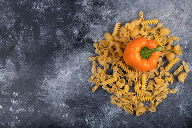 Peperone dolce con pasta cruda secca su marmo.