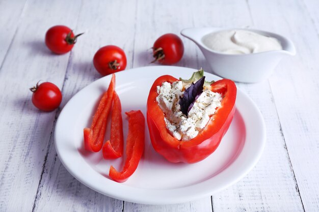 Peperone ripieno sulla barca del piattino del piatto e pomodori su fondo di legno