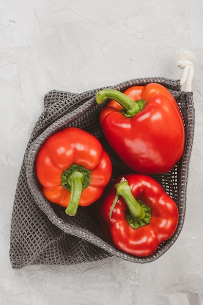 Peperone rosso dolce maturo biologico fresco in borsa ecologica riutilizzabile su spazio di copia grigio