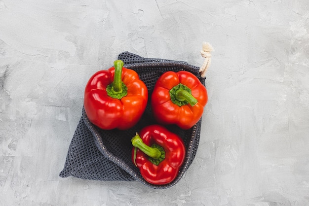 Peperone rosso dolce maturo biologico fresco in borsa ecologica riutilizzabile su spazio di copia grigio