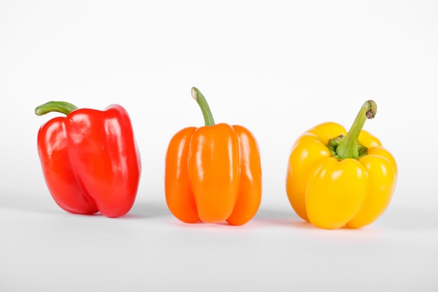 Peperoni di colore rosso, arancione e giallo su bianco