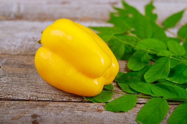 Peperoni gialli sugosi freschi dolci sul fondo di legno della tavola.