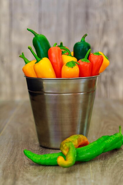 Peperoni gialli verdi rossi in un secchio peperoni e peperoncini rossi assortiti in un secchio di metallo con gocce d'acqua