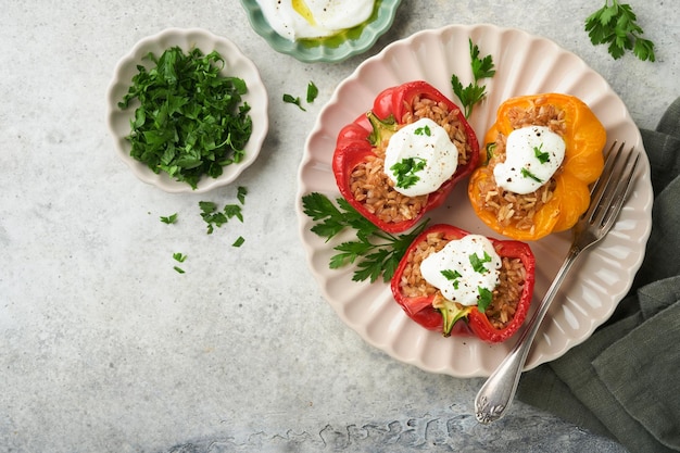 Peperoni rossi e gialli ripieni arrosto con cous cous di riso integrale e farro con salsa greca e olio d'oliva su fondo di legno rustico Cena sana Mangiare Autunno accogliente cena concetto Vista dall'alto