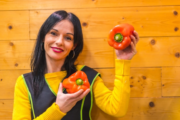 Peperoni rossi in mano a una ragazza bruna caucasica di frutta, che lavora in un fruttivendolo