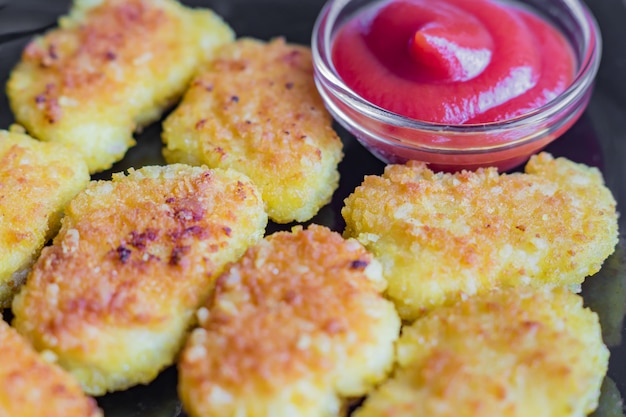 Pepite di pollo croccanti fritte con ketchup su una banda nera