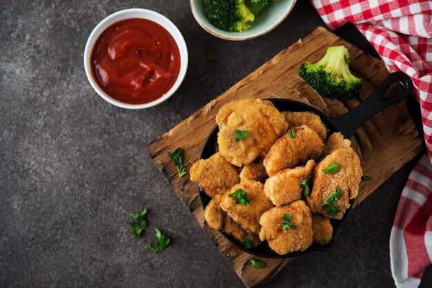 Pepite di pollo fatte in casa con verdure su una tavola di legno